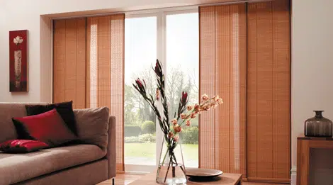 Modern living room with brown woven vertical blinds on sliding glass doors, providing privacy and a warm, stylish aesthetic.